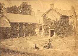 P6A/966 Armstrong collection: photograph of Moyaliffe Castle showing the south wing and garden, with Captain Edward Armstrong and his wife Frances née Steele seated on a bench [c1870s]. © Glucksman Library, University of Limerick.